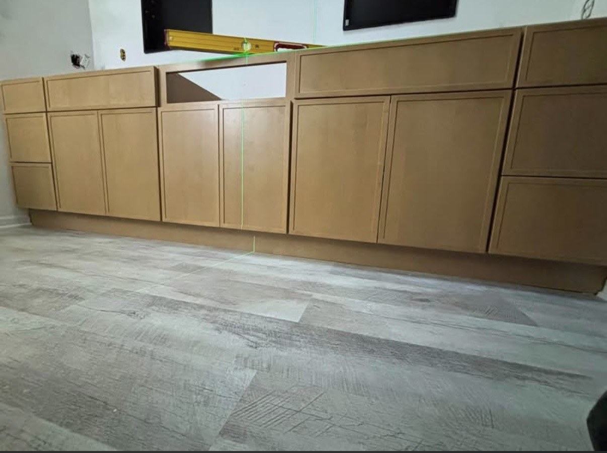 Wood base cabinets during installation above gray plank flooring