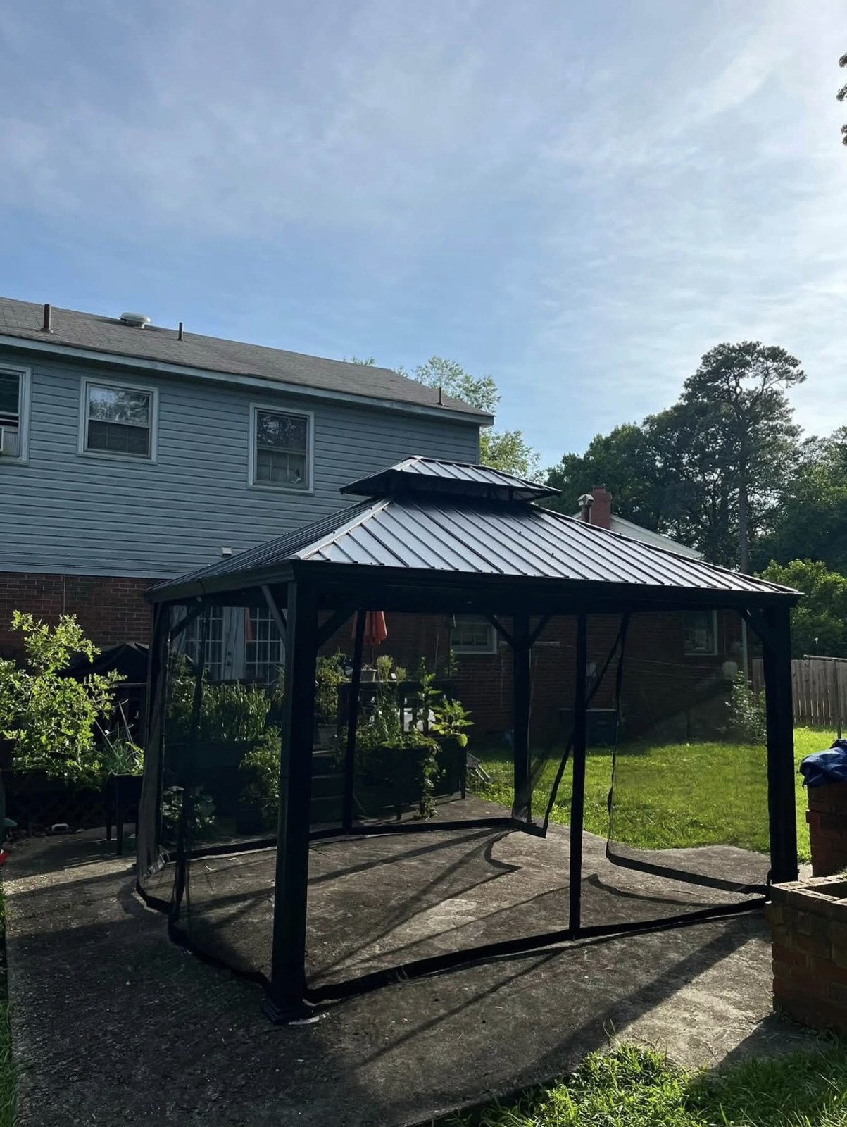 Dark metal-roof gazebo with mesh screens on a backyard patio
